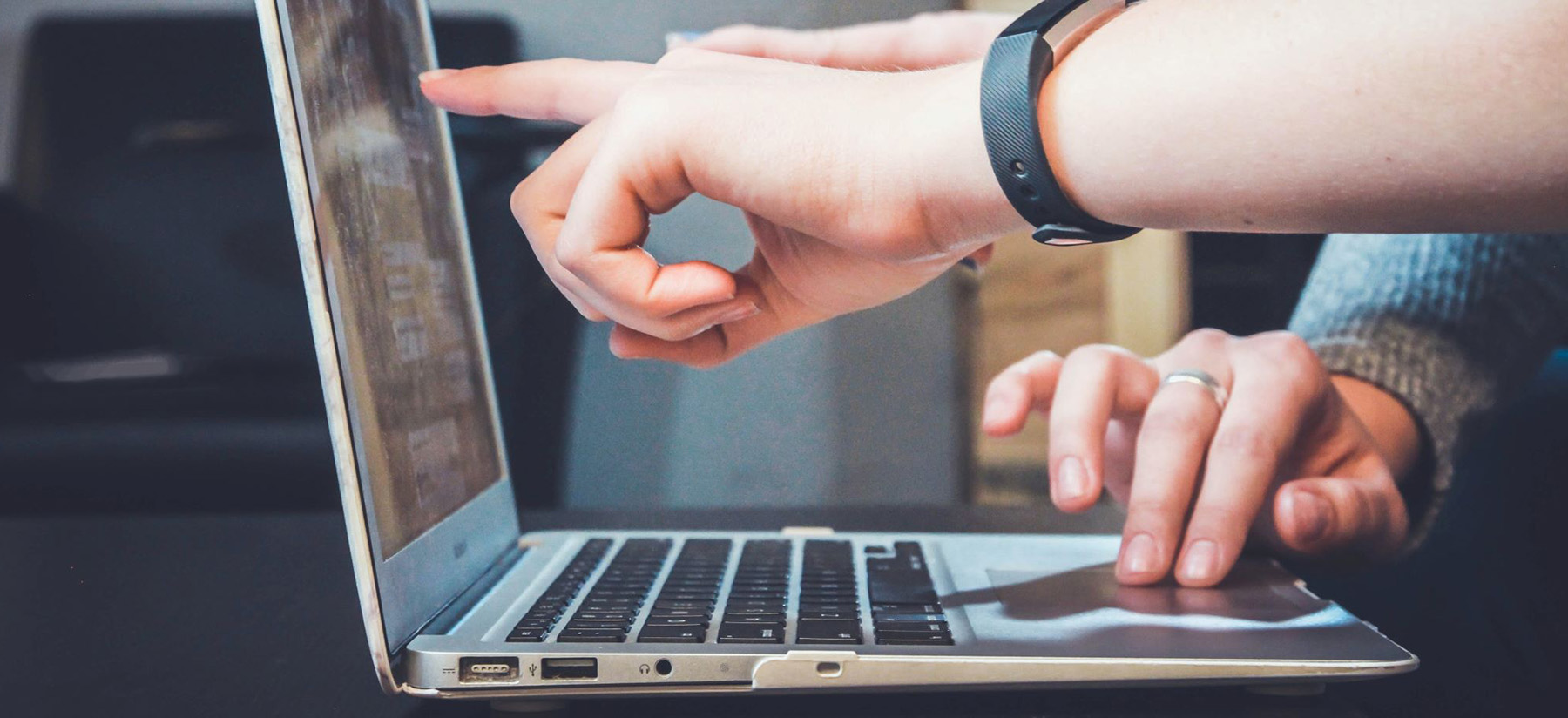 Person pointing at a computer screen.